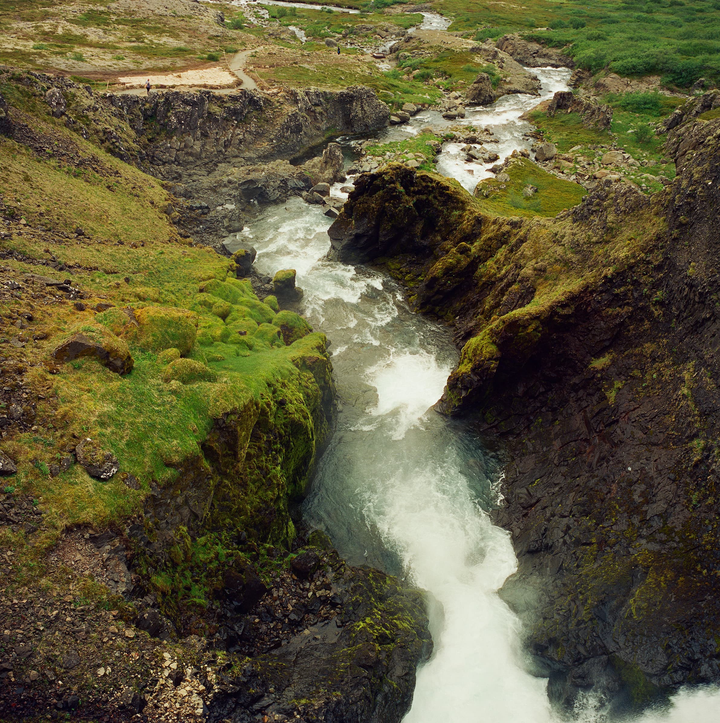 The thundering cascade of Dynjandi waterfall rushing over moss-covered rocks viewed from above