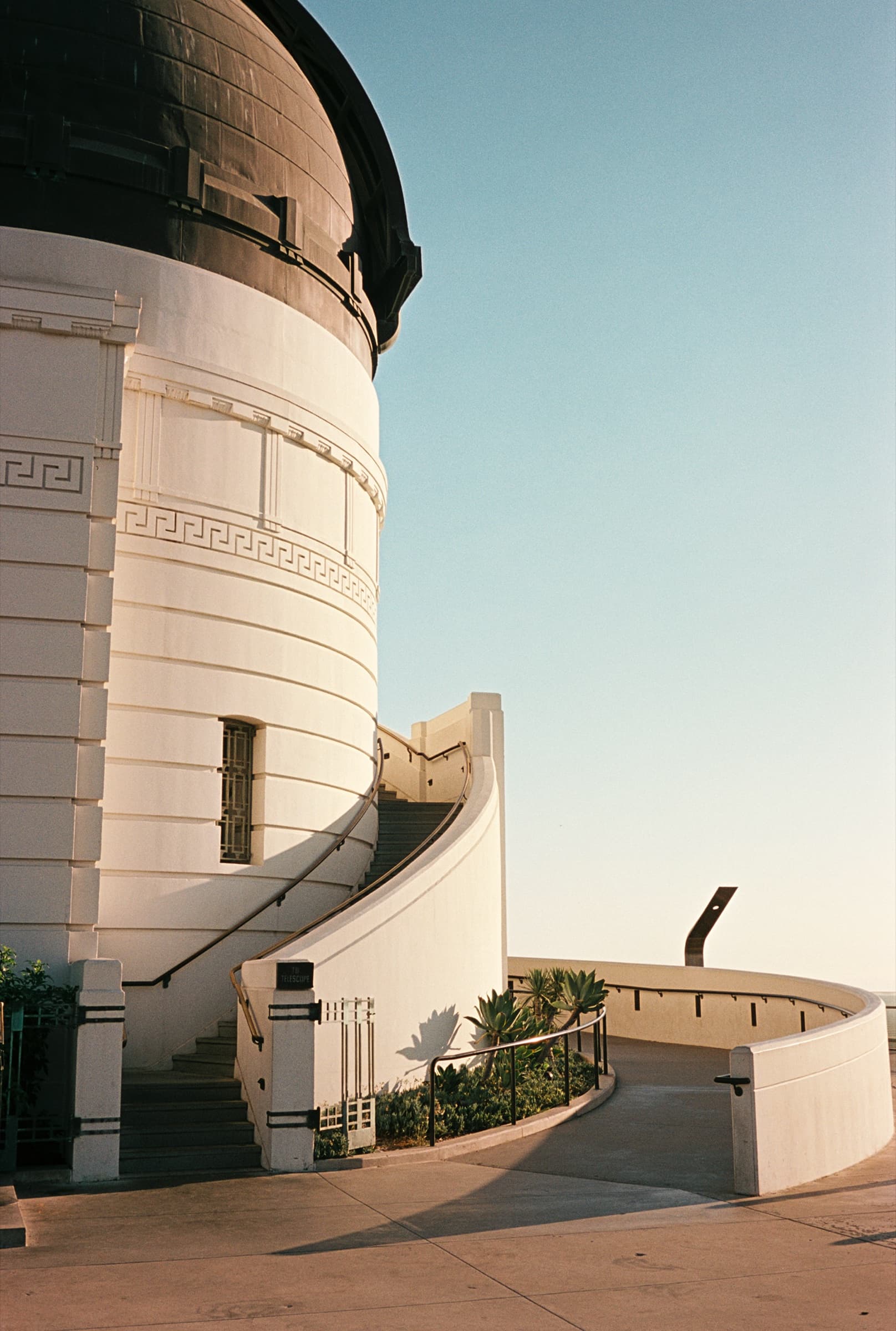 Looking up at the white Art Deco dome of Griffith Observatory against a clear blue sky