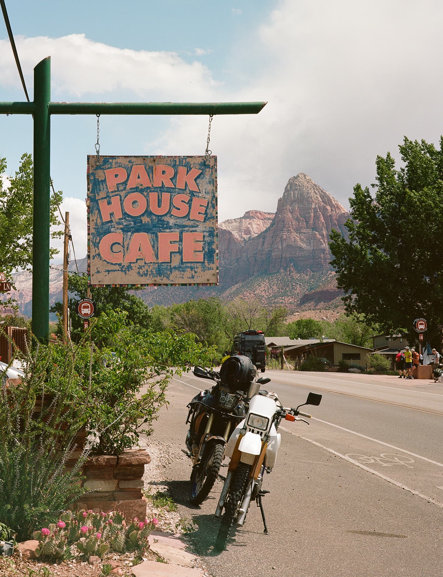The Park House Cafe sign with a parked motorcycle and Zion's red canyon walls looming behind