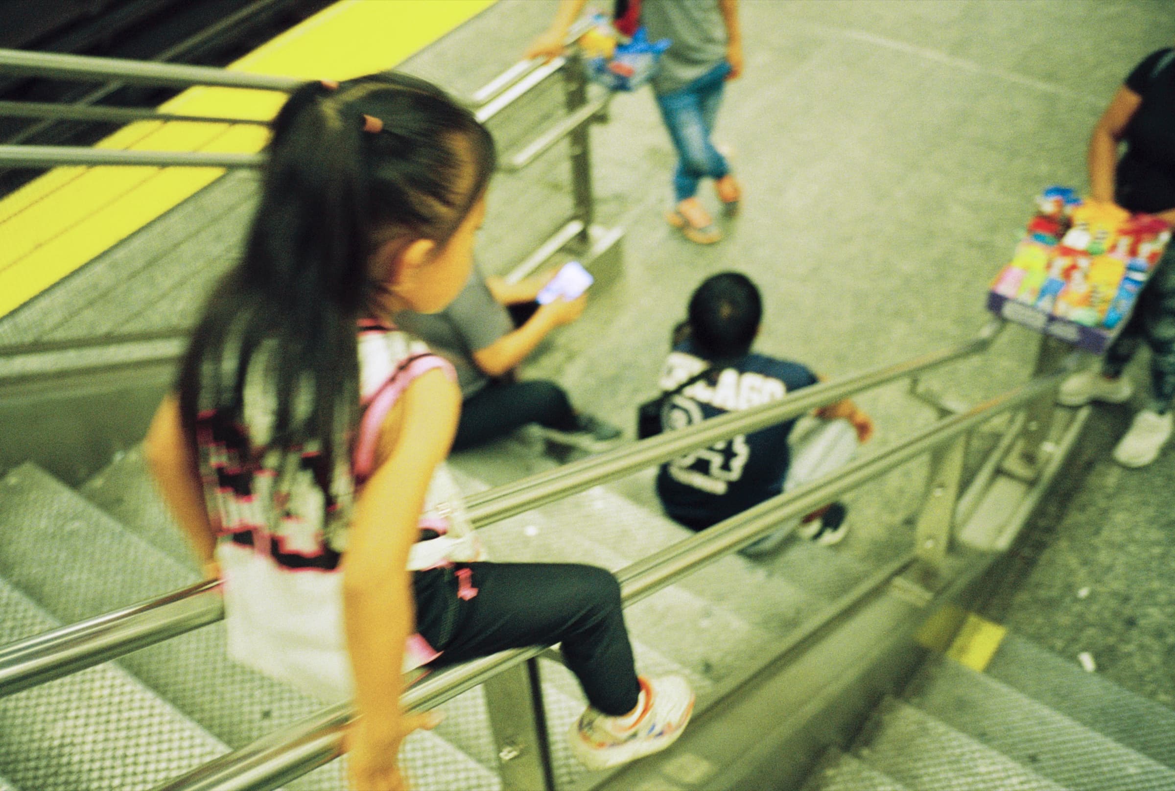 Child sliding down a handrail on a subway platform in New York